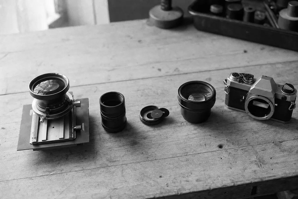 Fotografisches Zubehör in einer Reihe auf einer Werkbank, darunter Objektiv, Schneckengang und Nahlinse (mit AI erstelltes Bild)